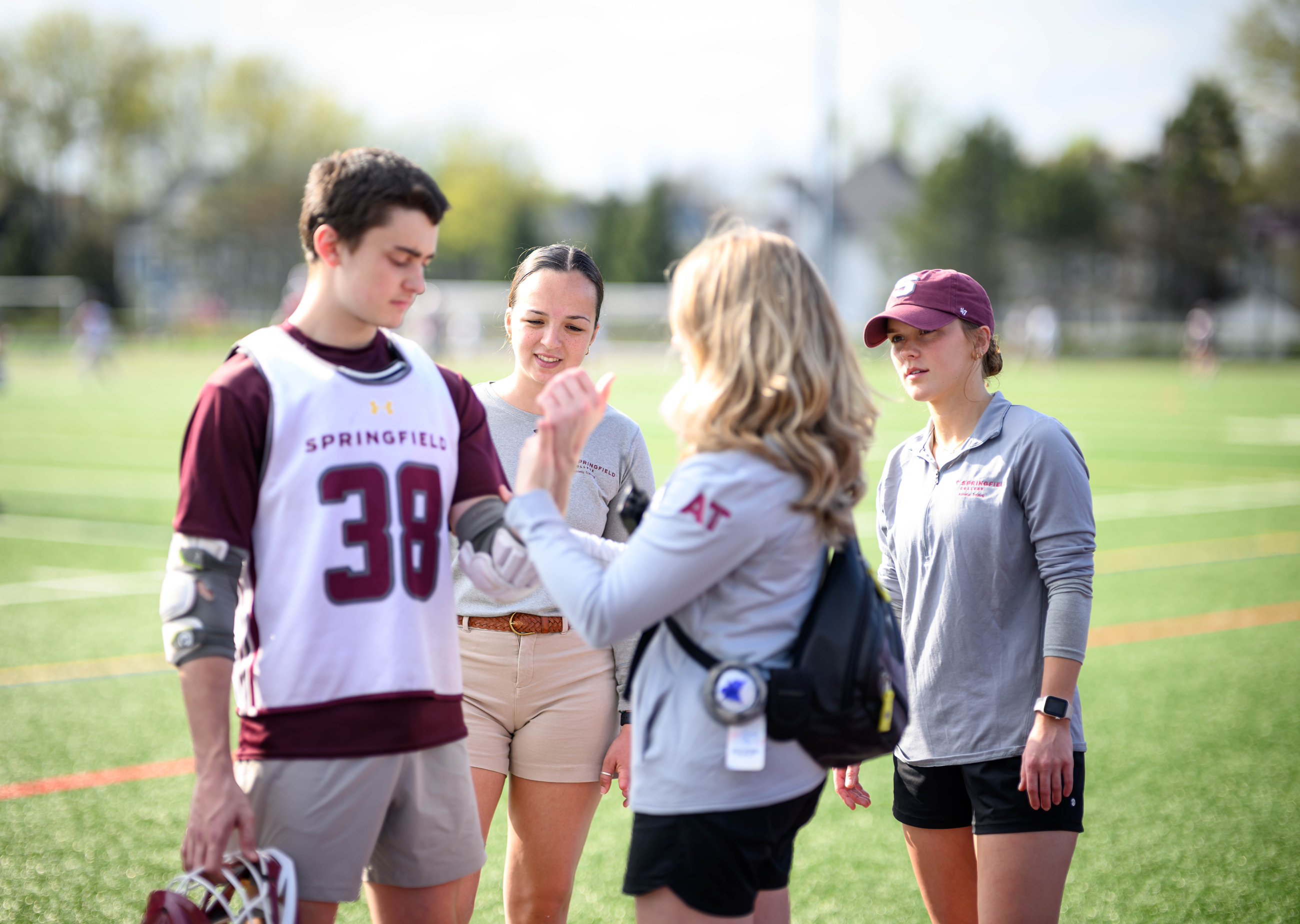 female trainer helping male lacrosse player